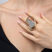 Close-up of handmade open frame crystal ring with large oval gold outline on the hand