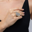 Hand wearing geometric crystal statement ring with black V-neck dress, Glitter Kiss collection
