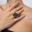 Close-up of sculptural gold ring with faceted crystal panel on the middle finger