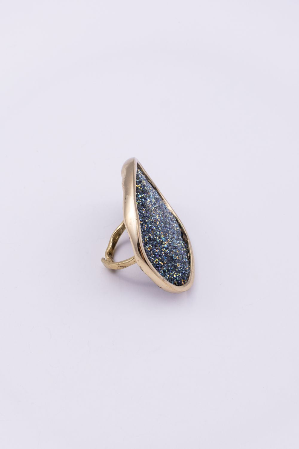 Side view of handmade gold ring with oval crystal surface and hammered open band