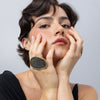 Woman wearing handmade oval crystal ring with slim gold frame, hands framing the face