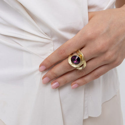 Woman wearing the Shiny Boteh gold-plated statement ring with a large purple amethyst-colored crystal and textured bands, Savage Flora