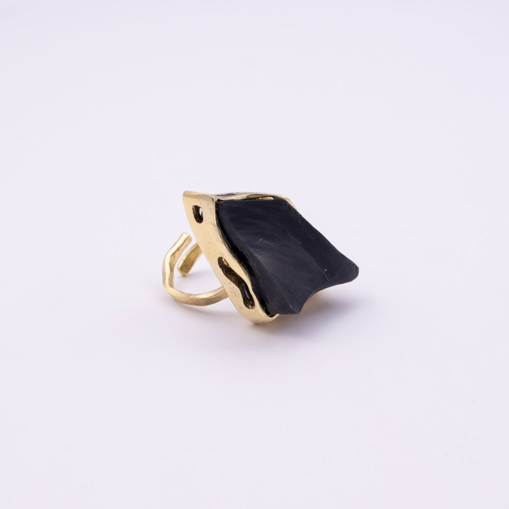 Kite handmade gold-plated cocktail ring with black raw-cut stone and open branch-style band on a white background
