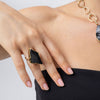 Woman wearing the Kite gold-plated brass statement ring with a large black raw-cut stone, Savage Flora
