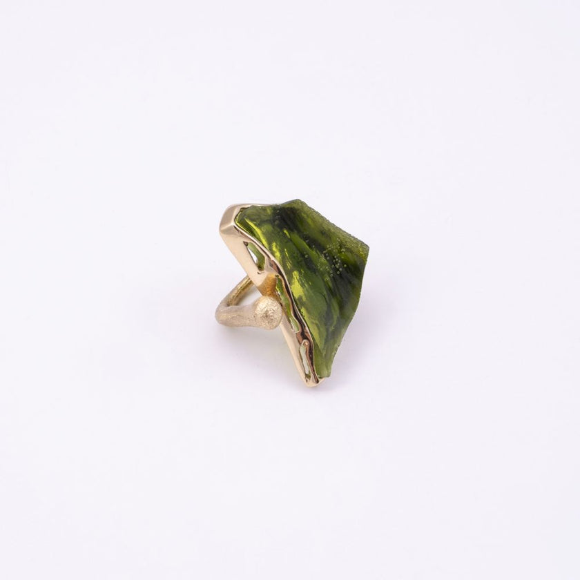 Kate handmade gold-plated statement ring with an olive green resin stone and open adjustable band, angled view on white background