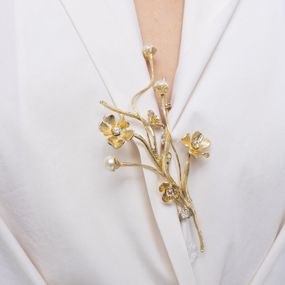 Brass flower pin with pearl buds and colored crystals worn on lapel