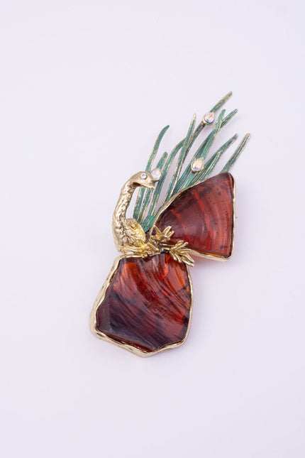 Plume handmade gold-plated brass peacock pin with amber resin stones and green patina feathers on a white background