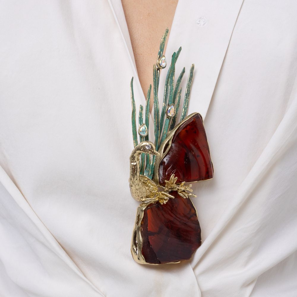 Woman wearing the Plume peacock statement brooch with large amber resin stones, green patina feathers and iridescent crystals, Savage Flora