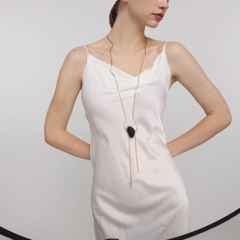 Elemental Pebble Necklace angle view — handmade brass sculptural necklace with rounded stone centerpiece