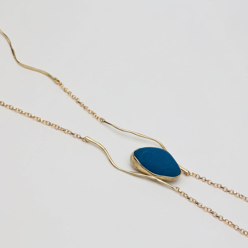 Elemental Pebble Necklace — handmade brass necklace with raw resin stone pendant, top down view on white background