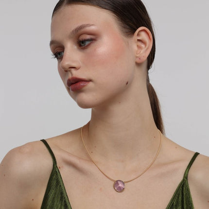Kiss Necklace close-up — handmade brass setting holding a smooth raw resin stone pendant