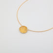 Kiss Necklace — handmade brass wire choker with smooth pebble stone, hanging view on white background