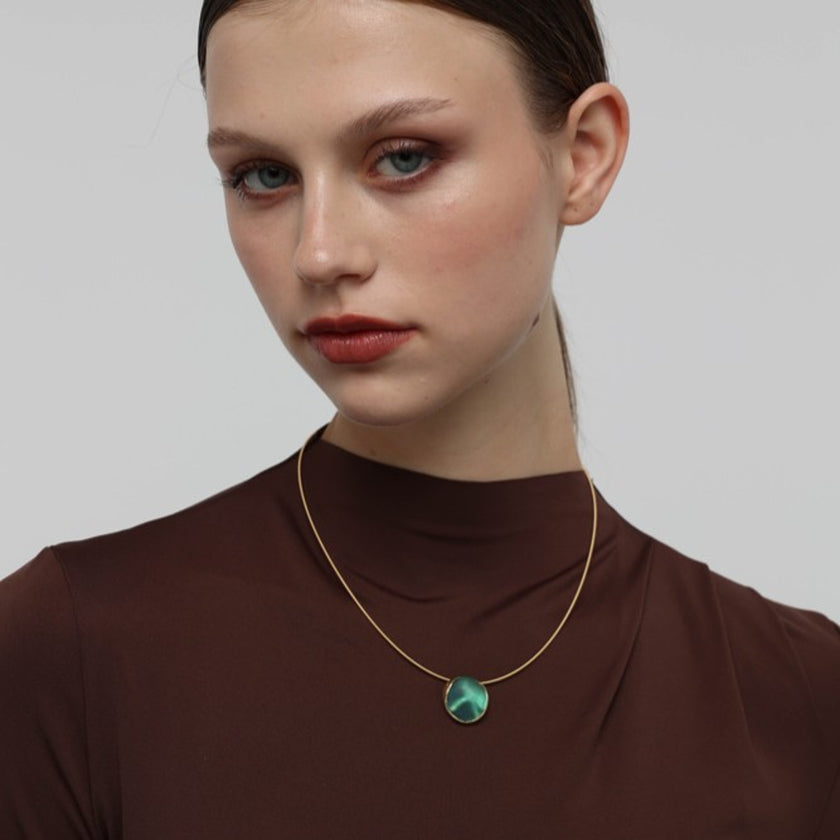 Kiss Necklace detail — handmade brass pendant with organic resin stone set in brass