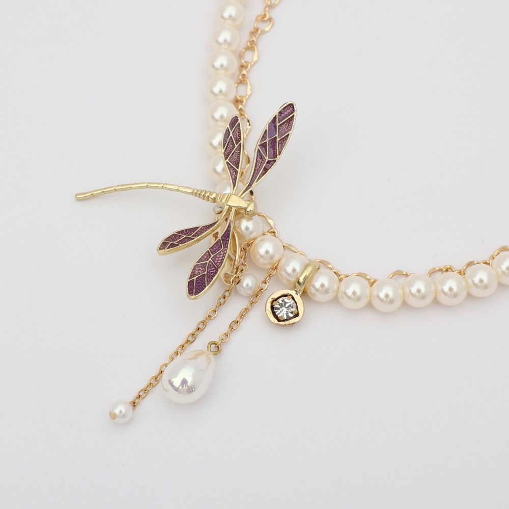 Pearl necklace with a dragonfly charm on a light gray background