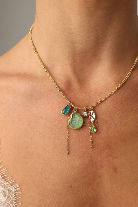 Shelly Necklace close-up — artisan brass jewelry cluster with crystal charms and a swirled shell pendant