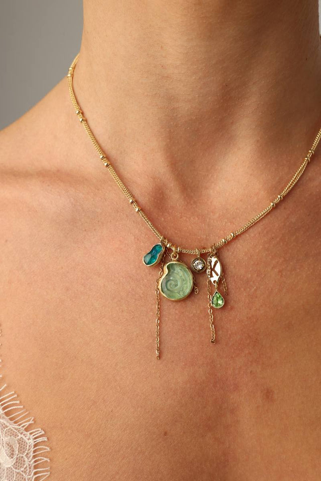 Shelly Necklace close-up — artisan brass jewelry cluster with crystal charms and a swirled shell pendant