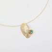 Gold necklace with a textured pendant and blue gemstone on a white background
