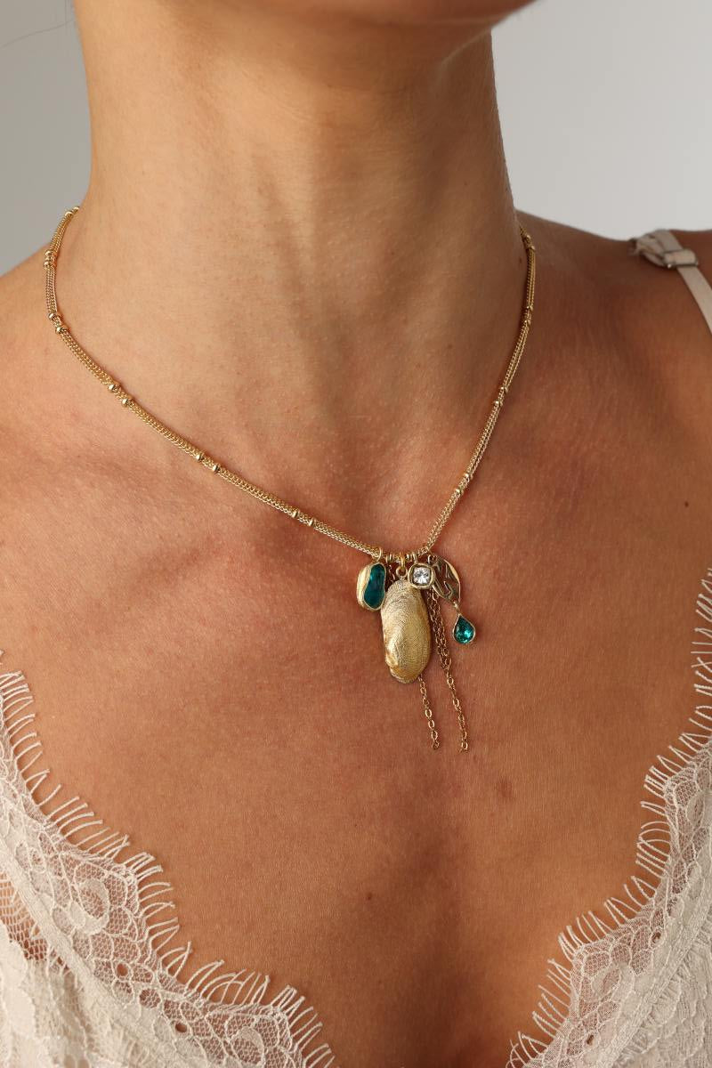 Charmy Limpet Necklace close-up — artisan brass jewelry cluster with crystal charms and a textured limpet pendant