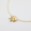 Tide Necklace flat lay — beautiful pearl and brass sea motif necklace, made in Greece