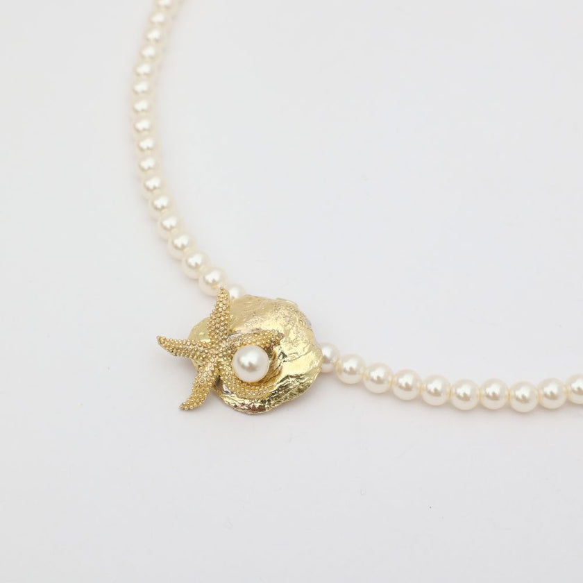 Tide Necklace flat lay — beautiful pearl and brass sea motif necklace, made in Greece