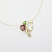 Necklace with a gold leaf pendant featuring a purple and green stone on a white background