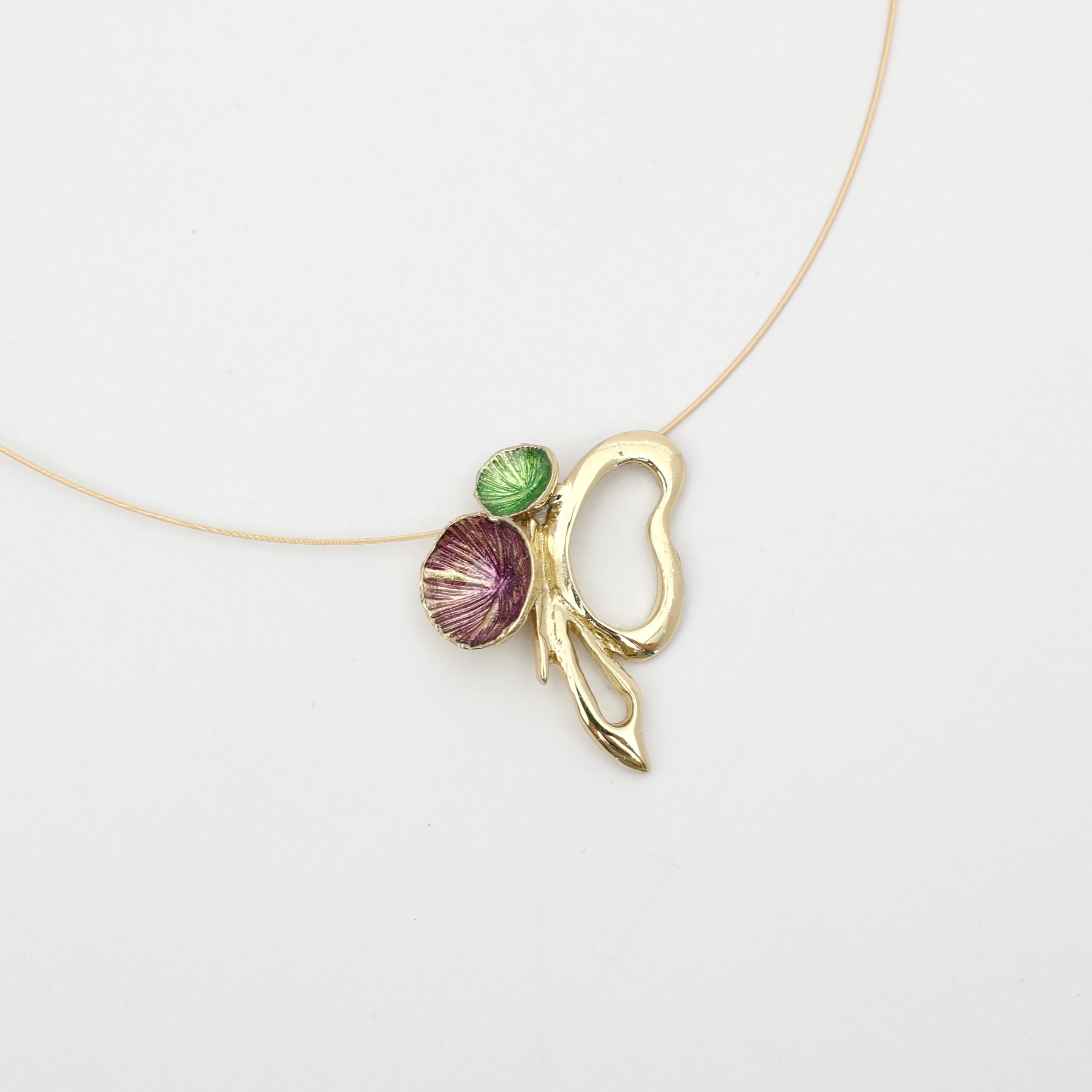 Necklace with a gold leaf pendant featuring a purple and green stone on a white background