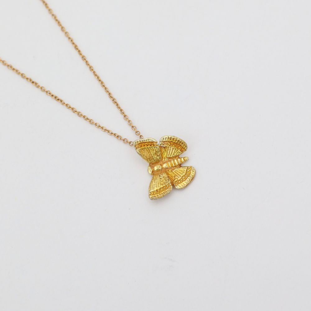 Gold butterfly pendant necklace on a light gray background