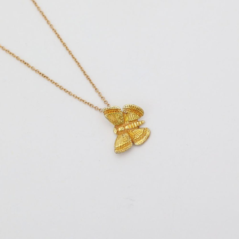 Gold butterfly pendant necklace on a light gray background