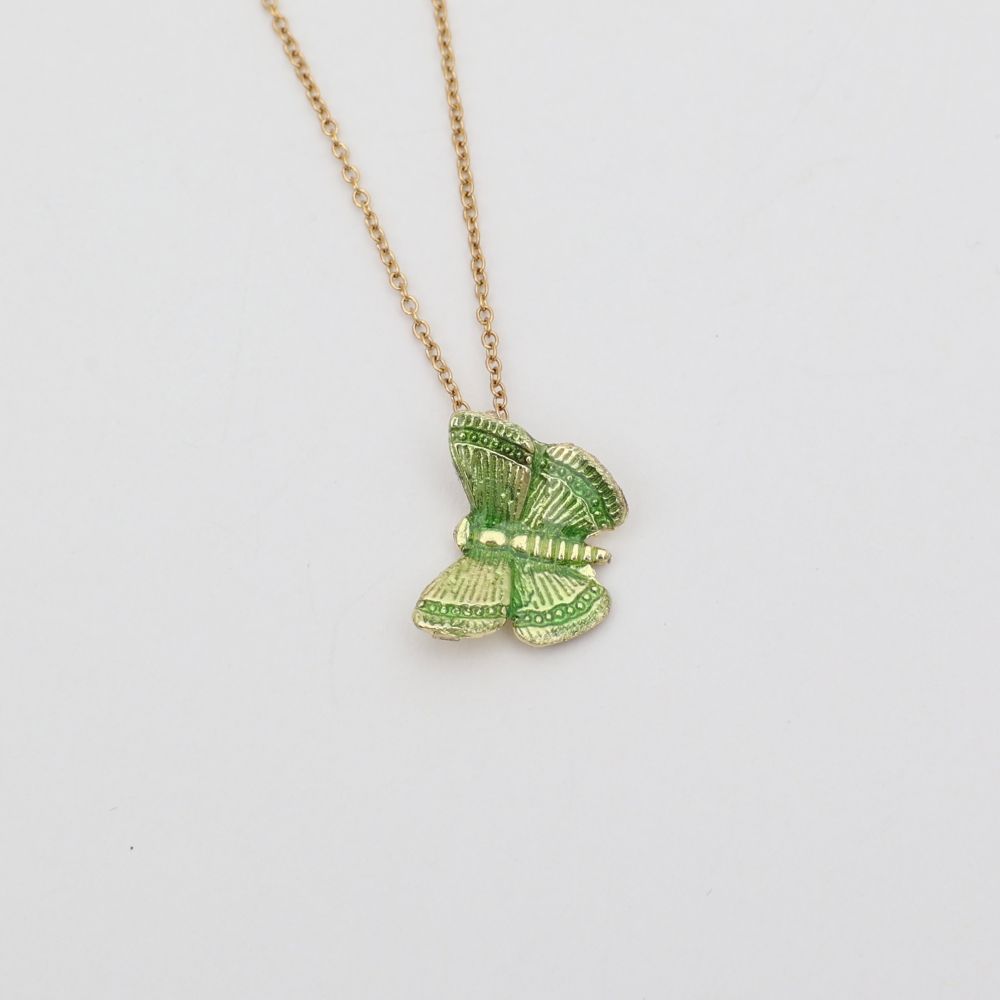Gold butterfly necklace on a light gray background
