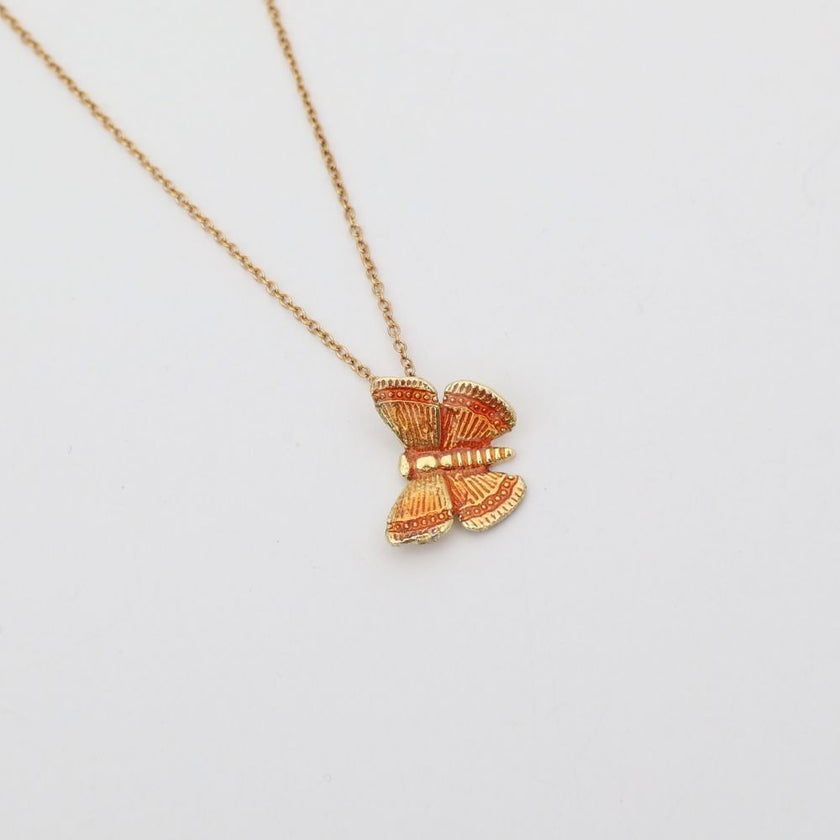 Gold butterfly pendant necklace on a light gray background