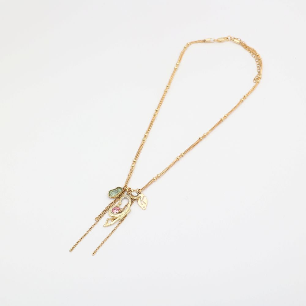 Gold necklace with charms on a light gray background