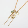 Gold necklace with various charms on a light gray background