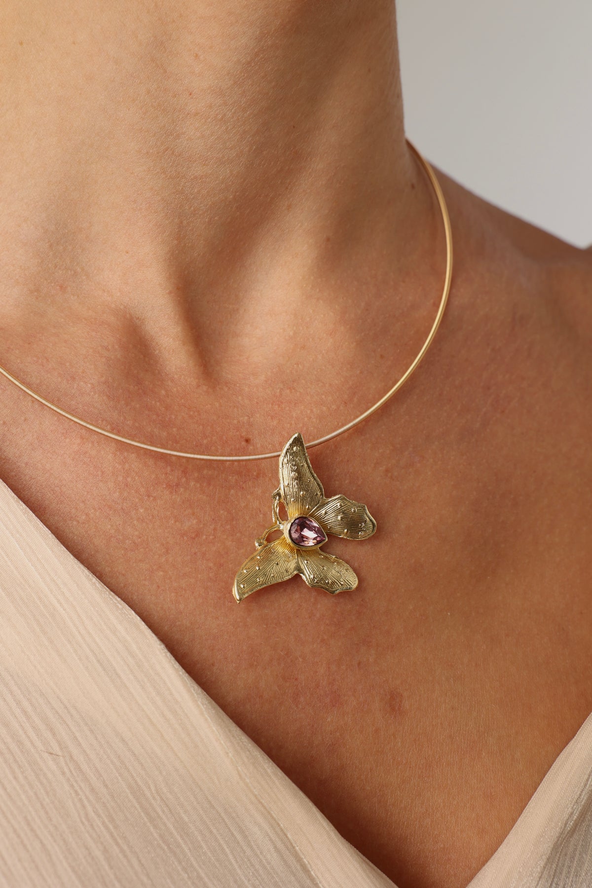 Nymia Necklace — handmade brass butterfly statement necklace with pink teardrop gemstone, worn on model