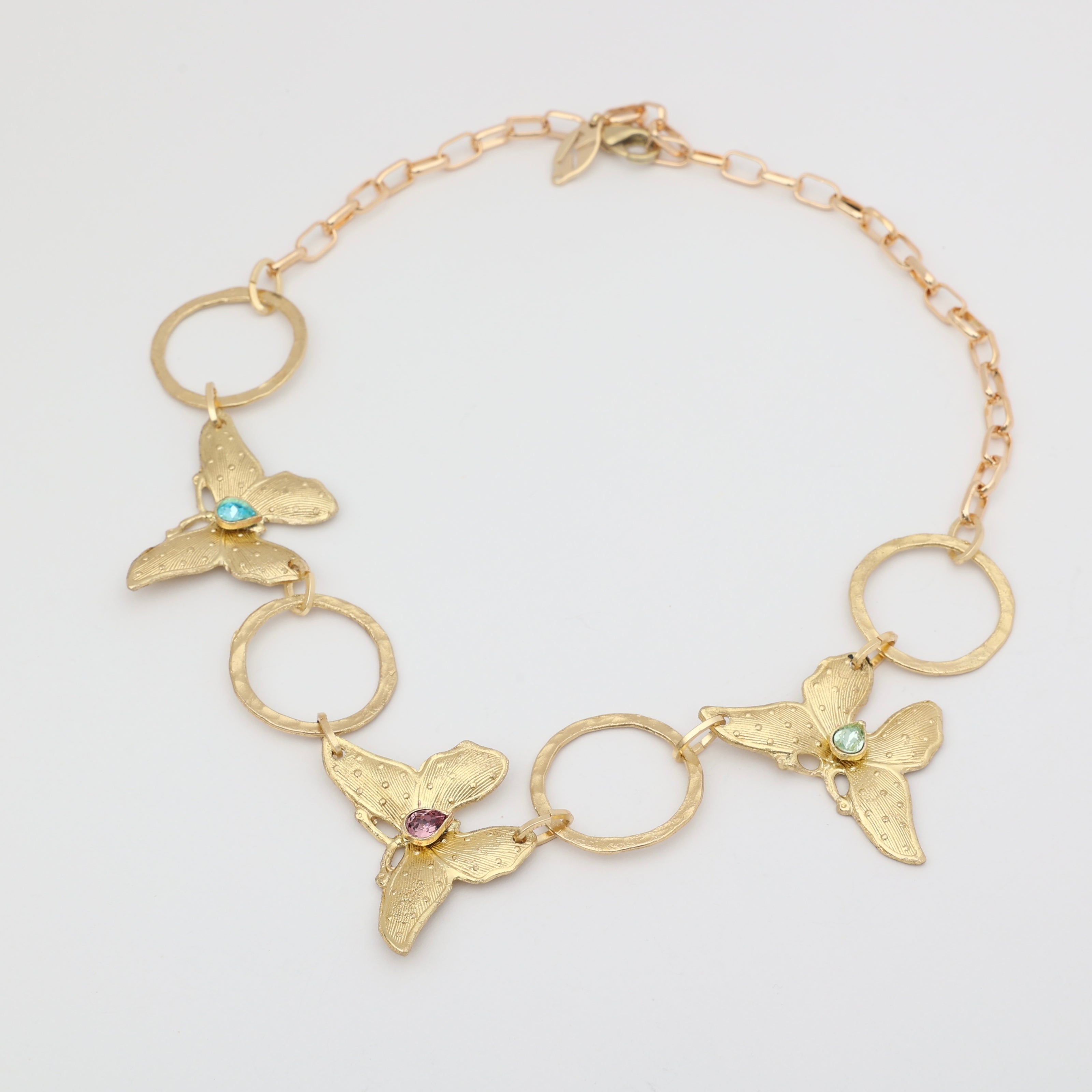 Nymia handmade gold brass butterfly choker necklace with open ring chain links and multicolor crystal gemstones flat lay view