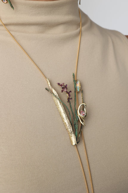 Fiora botanical wearable art necklace with opal and pink tourmaline pendant worn on a beige ribbed turtleneck