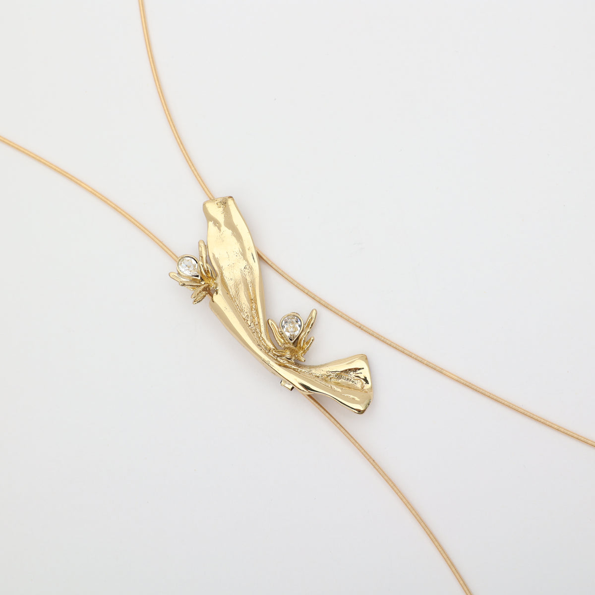 Navily Necklace flat lay, handmade brass lariat pendant with white crystal version, made in Greece.