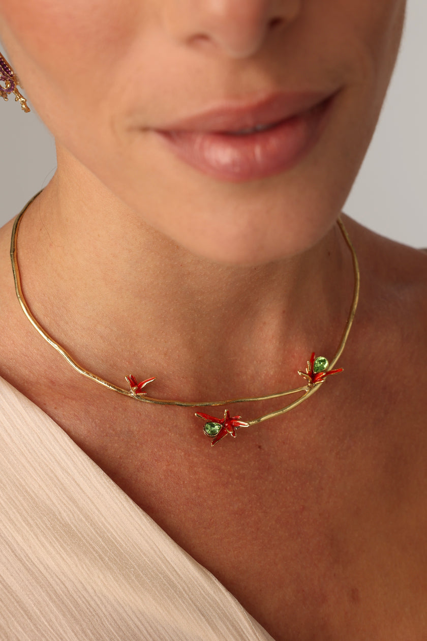 Close-up of a woman wearing a gold necklace with floral elements.