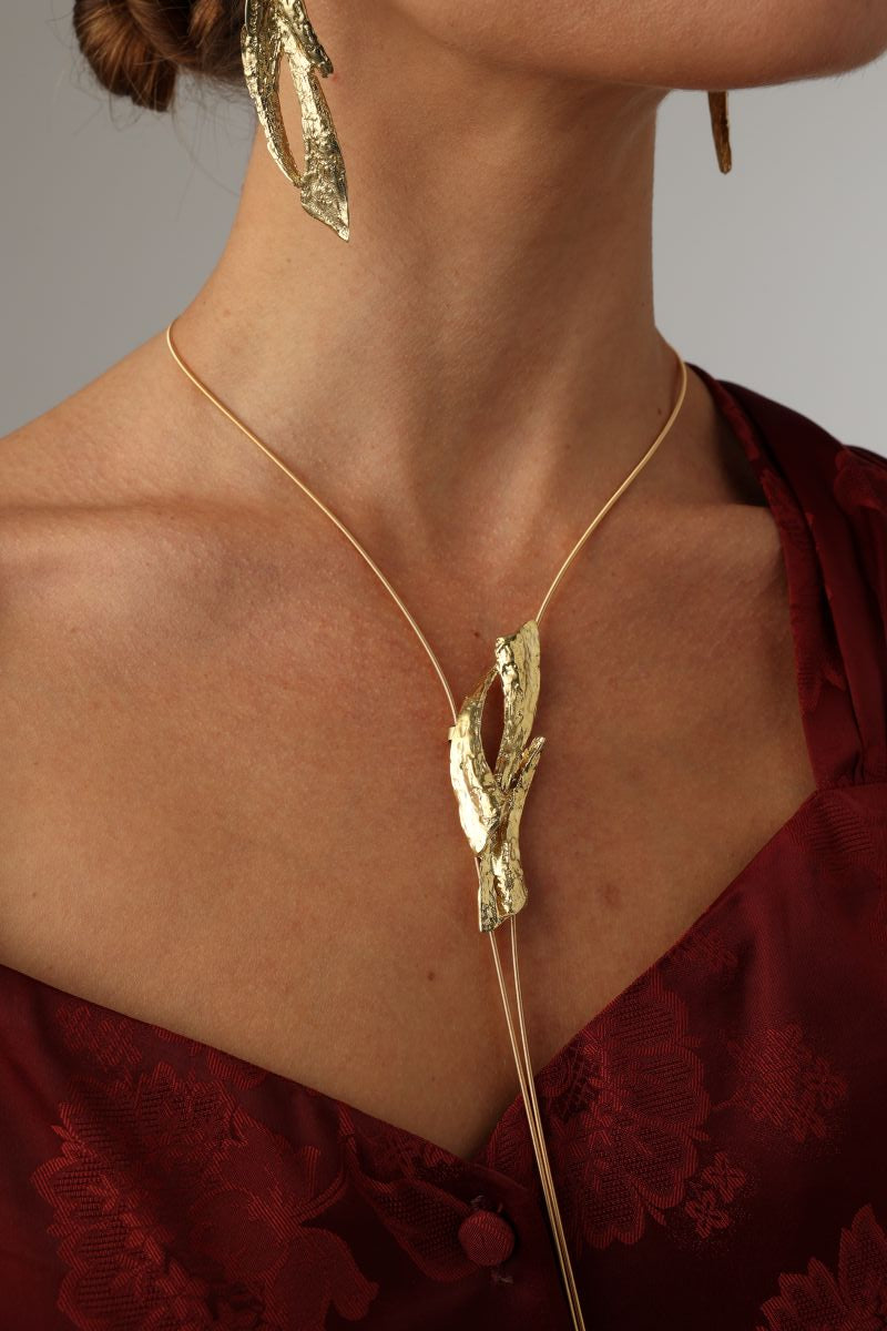 Dragonfish Necklace — handmade brass sculptural lariat necklace with raw pendant on model, styled with matching earrings