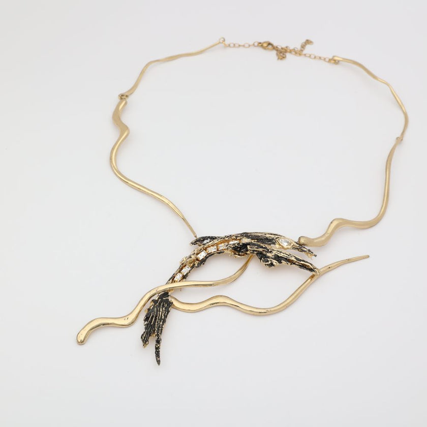 Dragon Necklace — handmade brass sculptural statement necklace with oxidized pendant and baguette crystals, flat lay