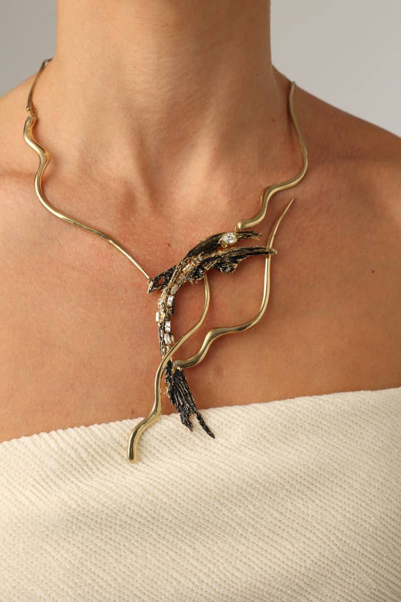 Dragon Necklace — handmade brass sculptural statement necklace with wave collar and oxidized crystal pendant on model, close-up