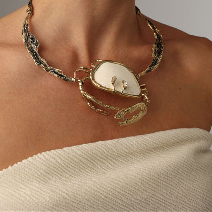 Crasta Necklace — handmade brass sculptural statement necklace with natural stone crab pendant on model, styled with matching earrings