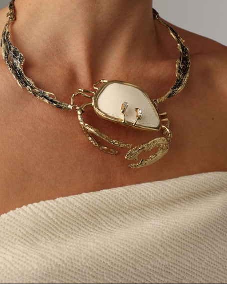 Crasta Necklace — handmade brass sculptural statement necklace with natural stone crab pendant on model, styled with matching earrings