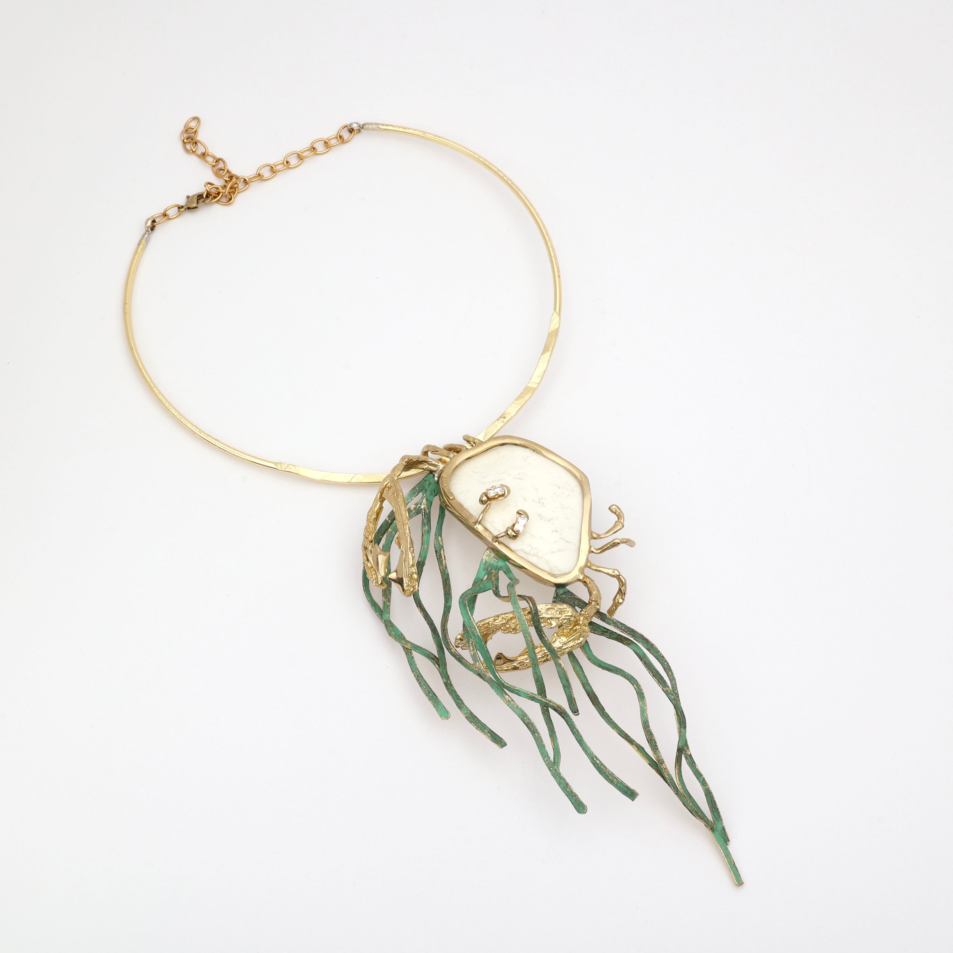 Kora Necklace flat lay — handmade brass artisan crab necklace with resin stone and flowing brass tentacles
