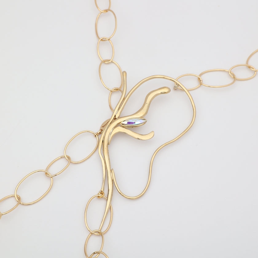 Flat lay close-up of handmade brass abstract pendant with iridescent marquise crystal and oval link chain, unique Greek designer jewelry.