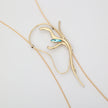 Flat lay of handmade brass abstract lariat necklace with aqua blue crystal, unique Greek designer jewelry.