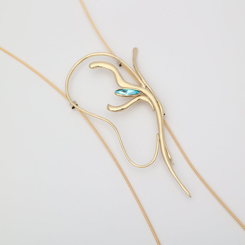 Flat lay of handmade brass abstract lariat necklace with aqua blue crystal, unique Greek designer jewelry.