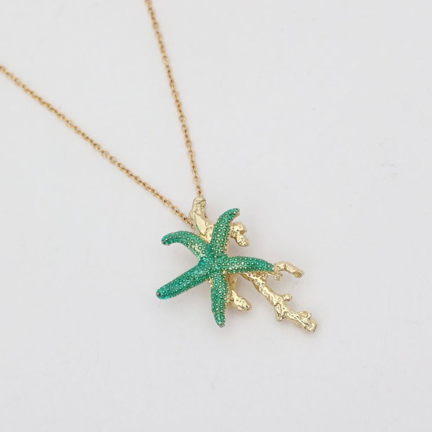 Astel Necklace — handmade brass starfish pendant necklace with enamel and coral branch detail, flat lay