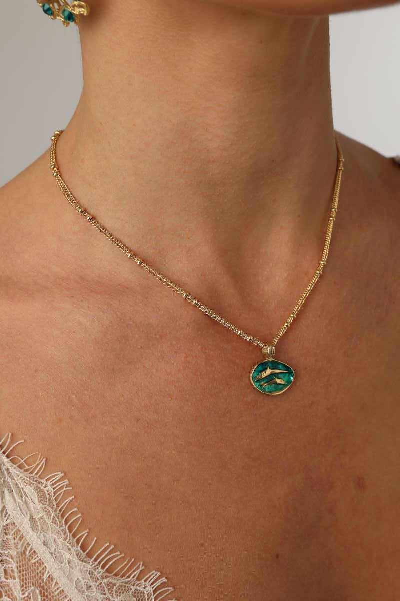 Delphi Necklace — handmade brass enamel pendant necklace with swallow motif on satellite chain, worn on model