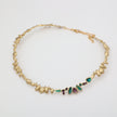 Gold necklace with embedded gemstones on a light gray background