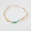 Gold necklace with green gemstones on a white background